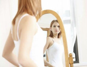 鏡をみて姿勢を気にする女性